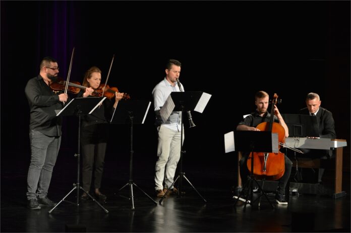 Obraz zawiera: pięć osób na scenie JDK: czterech mężczyzn i kobieta. Stoją: skrzypek, skrzypaczkai klarnecista, siedzą przed swoimi instrumentami: kontrabasista i organista
