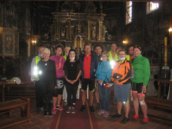 Uczestnicy wycieczki rowerowej oraz przewodniczka pozują wewnątrz kościoła do pamiątkowego zdjęcia