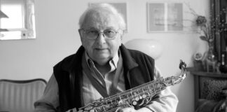 Zmarł Jerzy „Duduś” Matuszkiewicz Jerzy Matuszkiewicz. Muzyk w okularach lekko sie uśmiecha, w rękach trzyma saksofon.