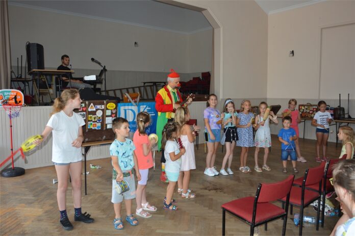 Dzieci z osiedla Hankówka wraz z klaunem Feliksem grają na instrumentach.