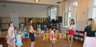 Bajkowe popołudnie z Myszką Miki Dwie dziewczynki trzymaja przeszkodę, pod którą muszą przejść pozostałe dzieci.