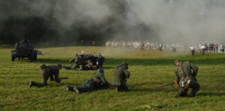 bitwa Polaków z niemieckim wrogiem. w tle publiczność widowiska na łąkach hubalowych. Inscenizacja historyczna