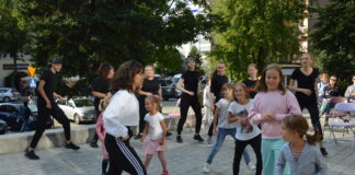Wakacyjny pociąg do kultury z JDK Grupa dzieic i młodzieży tańczy na tarasie Jasielskiego Domu Kultury