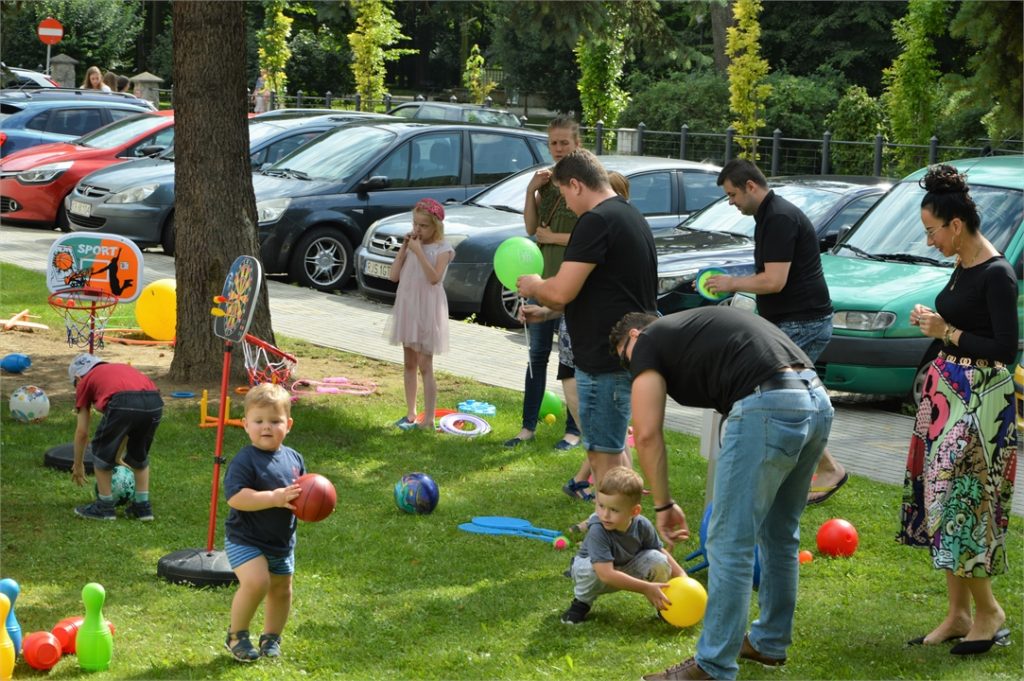 Dzieci bawią się piłkami na terenie zielonym przy Jasielskim Domu Kultury.