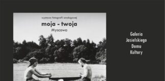 „Moja – twoja” Myscowa. Wystawa fotografii analogowej Wystawa fotografii analogowej - moja - twoja Myscowa. Dwóch mlodych mężczyzn siedzi naprzeciwko siebie trzymają w rękach piłę ręczną i tną deskę.