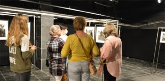 Finisaż w JDK. Codzienność podkarpackiej wsi na czarno-białej fotografii Grupa osób ogląda wystawę czarno - białych fotografii Myscowej