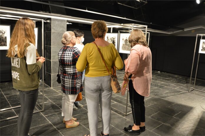 Grupa osób ogląda wystawę czarno - białych fotografii Myscowej