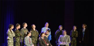 Fredro wciąż bawi Grupa aktorów na scenie. Na pirwszym planie trzy osoby siedzące, wokół nich kilkuosobowa grupa stojących