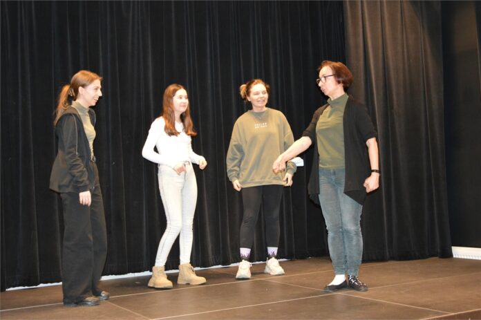 Obraz zawiera cztery osoby. Czterty osoby stoja na scenie podczas próby w tracie warsztatów teatralnych