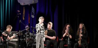 „Śpiewaj razem z nami” – podopieczni JDK nagrodzeni  na festiwalu w Przemyślu Obraz zawiera: Zespół Jazz Kids na scenie Cenrtum Kultury w Przemyślu. Na pierwszym planie chłopiec śpiewający do mikrofomu. Za nim siedzą muzycy saksofonista, trębaczka, saksofonistka. Z boku basista, a z tyłu perkusista.
