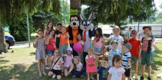 Bajkowe Show na osiedlu Mickiewicza Obraz zawiera: Dzieci z kciukami w górze pozują do wspołnego zdjęcia z Goofym i Królikiem Bugsem.