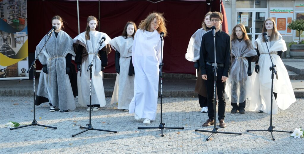 Obraz zawiera: uczestnicy Teatru Młodzieżowego JDK przedstawiają "Lilije" Adama Mickiewicza w ramach Narodowego Czytania 2022 na jasielskim rynku.