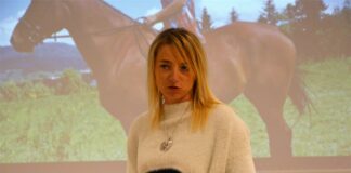 Obraz zawiera: na pierwszym planie gość klubu z pasją opowiada o swoich czworonożnych podopiecznych. Z tyły w tle ekran projektora na którym wyświetlone jest zdjęcie konia z jeźdźcem.