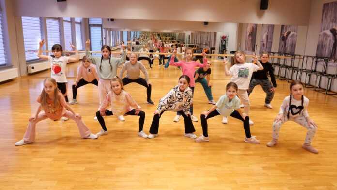 grupa dzieci w wieku od sześciu do dziesięciu lat tańczy podczas zajęć na sali tanecznej jasielskiego domu kultury