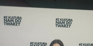 Sukcesy festiwalowe Karoliny Polak Karolina Polak ze statuetką w postaci mikrofonu oraz dyplomem. Za nią biały baner z czarnym napisem z kulturą nam do twarzy. Karolina ma na sobie czarną sukienkę na szelkach i ciemne rozpuszczone włosy