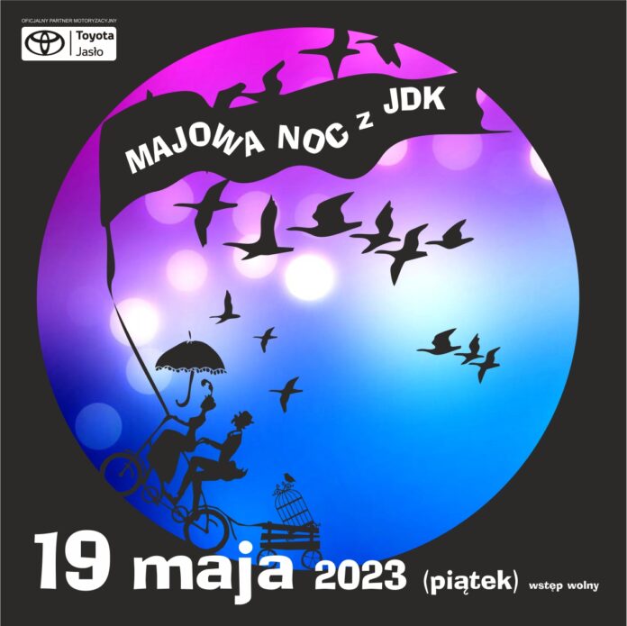 ikonka majowa noc baner na czarnym tle fioletowo granatowe koło. Na nim biały napis na czarnej fladze, majowa noc z jdk, pod nią czarne ptaki, na końcu flagi przyczepiona para jedzie na rowerze, ciągnie za sobą wózek z klatką. . Pod kołem białym kolorem napisana data.