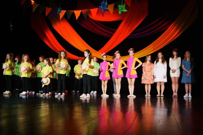 Na scenie, stojący recytatorzy, soliści i tancerze Jasielskiego Domu Kultury.