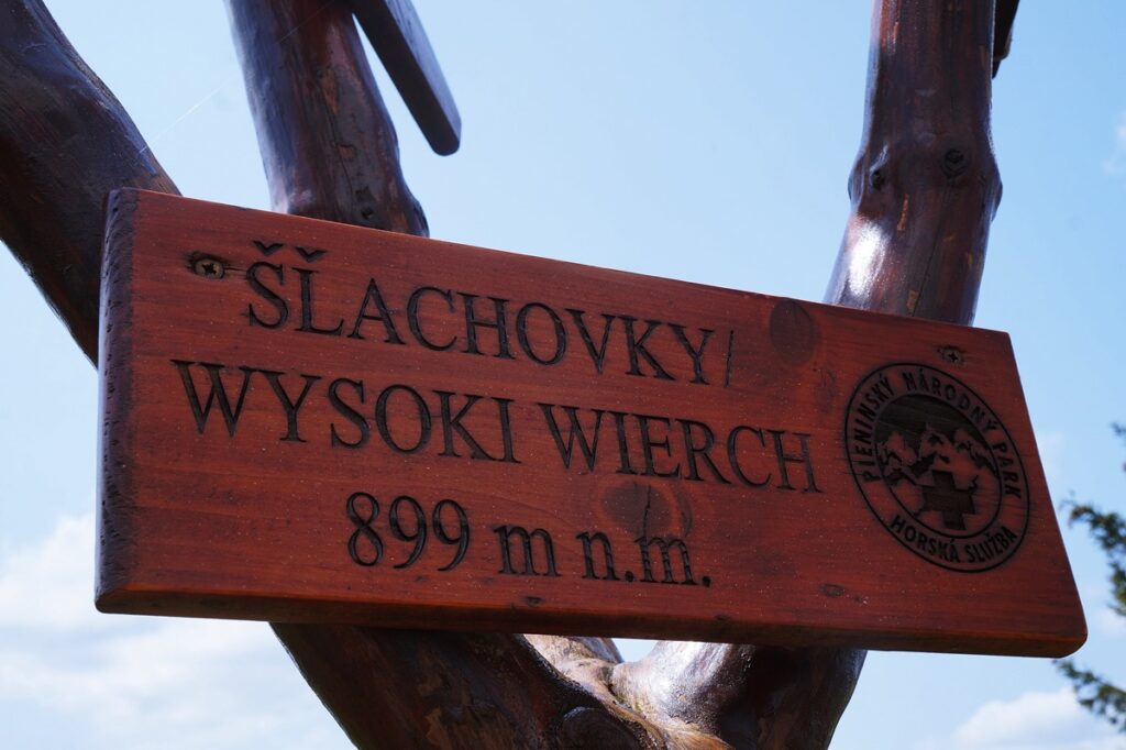 Znak informacyjny zdobytego szczytu: Wysoki Wierch. Informacja znajduje się na drewnianej tabliczce w języku polskim i słowackim. 