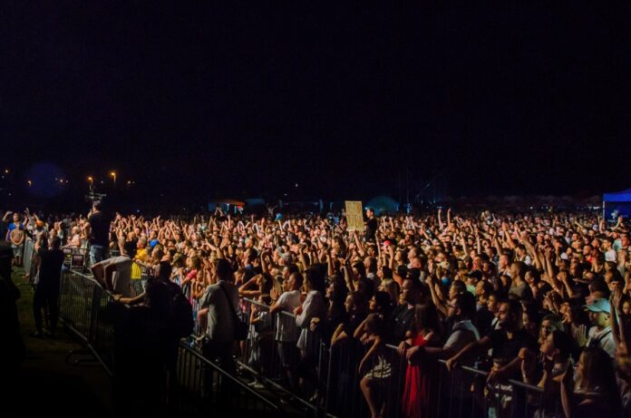 DSC_0668 Tłum ludzi na koncercie. Niektóre z osób unoszą dłonie w górę.