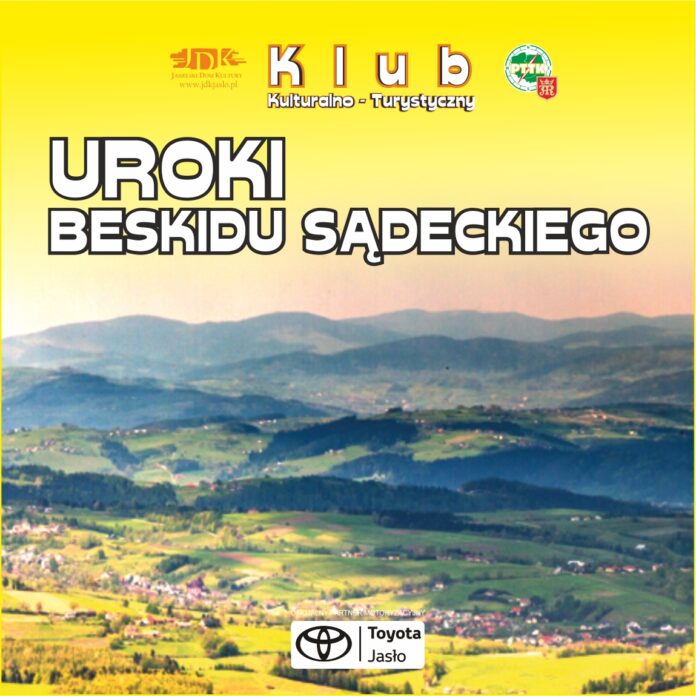 Na tle krajobrazu górskiego znajdują się białe napisy klub kulturalno-turystyczny a po jego bokach logotypy jasielskiego domu kultury po lewej stronie, natomiast po prawej polskiego towarzystwa turystyczno krajoznawczego. Na dole po środku baneru logotyp tojoty