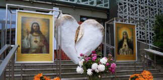 Ołtarz procesyjny z dużym, białym, pozłacanym sercem. Po jego obu stronach stoją dwa obrazy: Najświętszego Serca Pana Jezusa i Niepokalanego Serca Maryi. Całość zdobią kolorowe kwiaty.