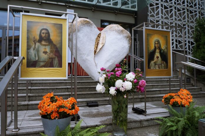 DSC04222 Ołtarz procesyjny z dużym, białym, pozłacanym sercem. Po jego obu stronach stoją dwa obrazy: Najświętszego Serca Pana Jezusa i Niepokalanego Serca Maryi. Całość zdobią kolorowe kwiaty.
