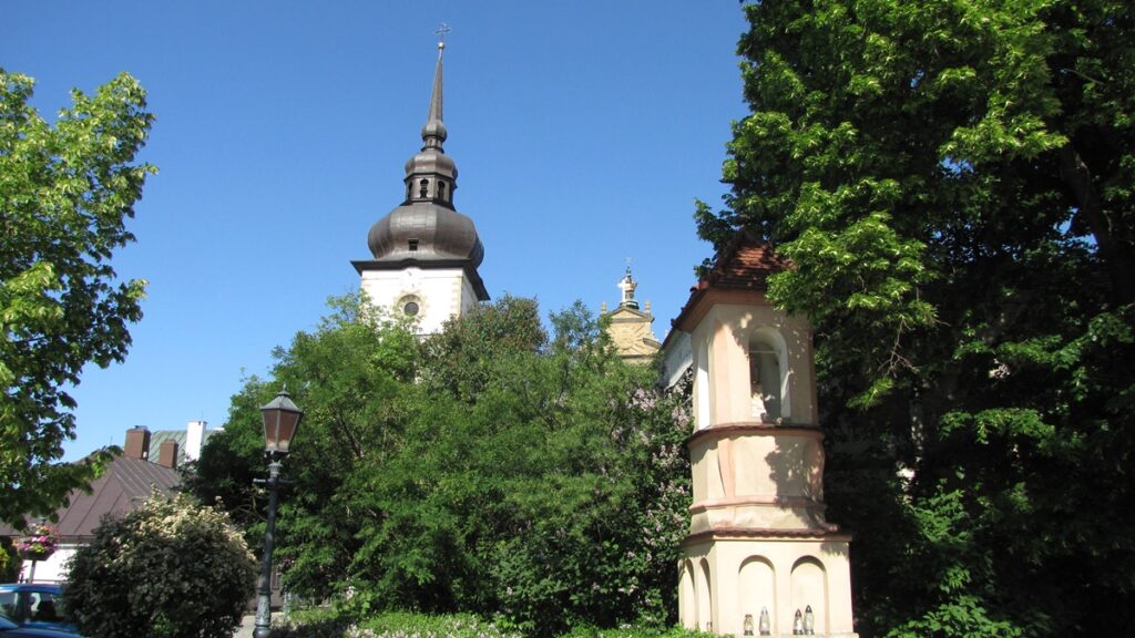 Sanktuarium św. Kingi. Dookoła rozrośnięte pięknie, zielone drzewa.