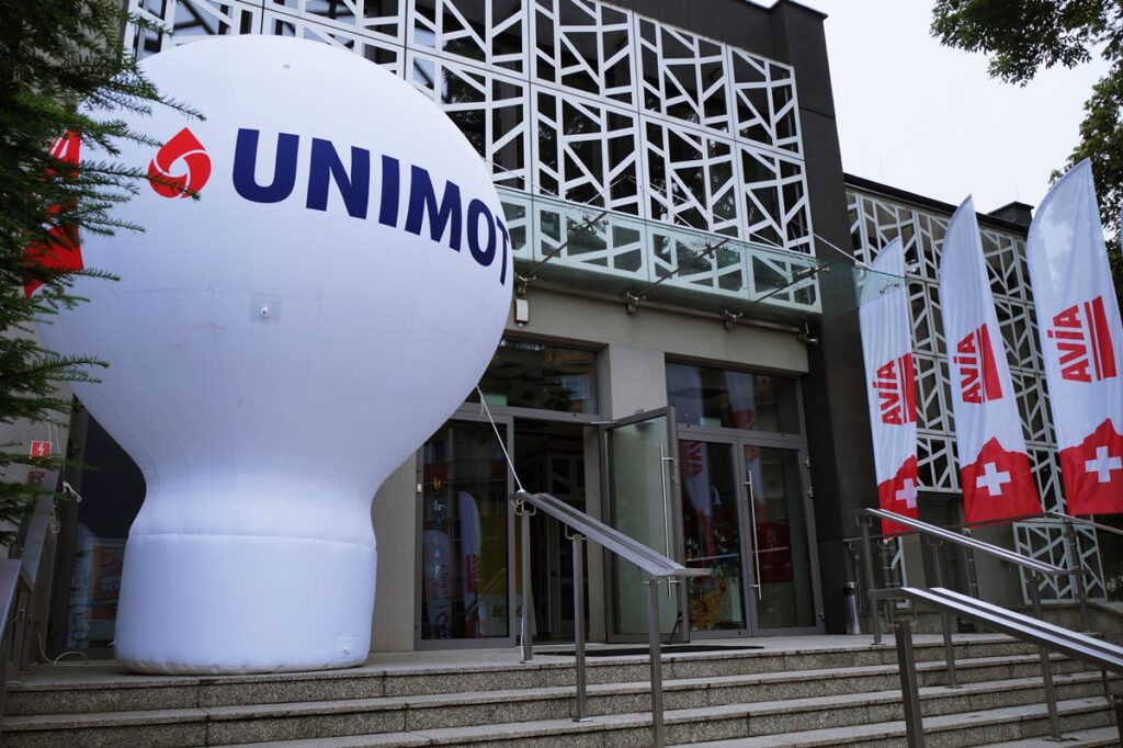 Budynek Jasielskiego Domu Kultury. Wejście główne. Obok duży biały, dmuchany balon firmy Unimot oraz biało-czerwone, powiewające na wietrze flagi Avia. 