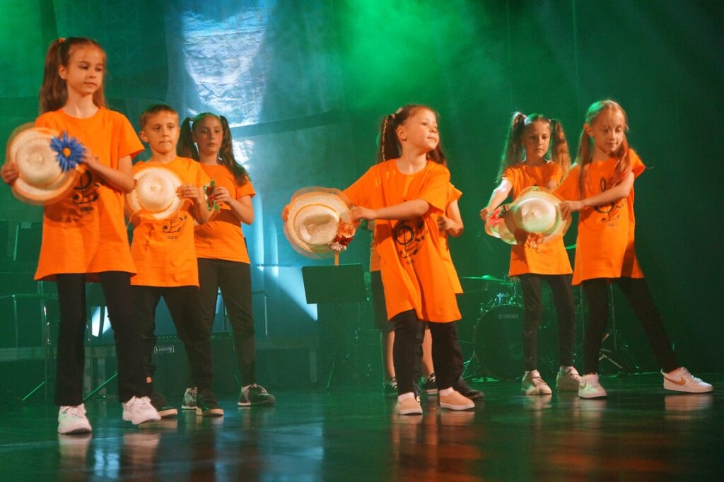 Grupa dzieci tańczy na scenie. 