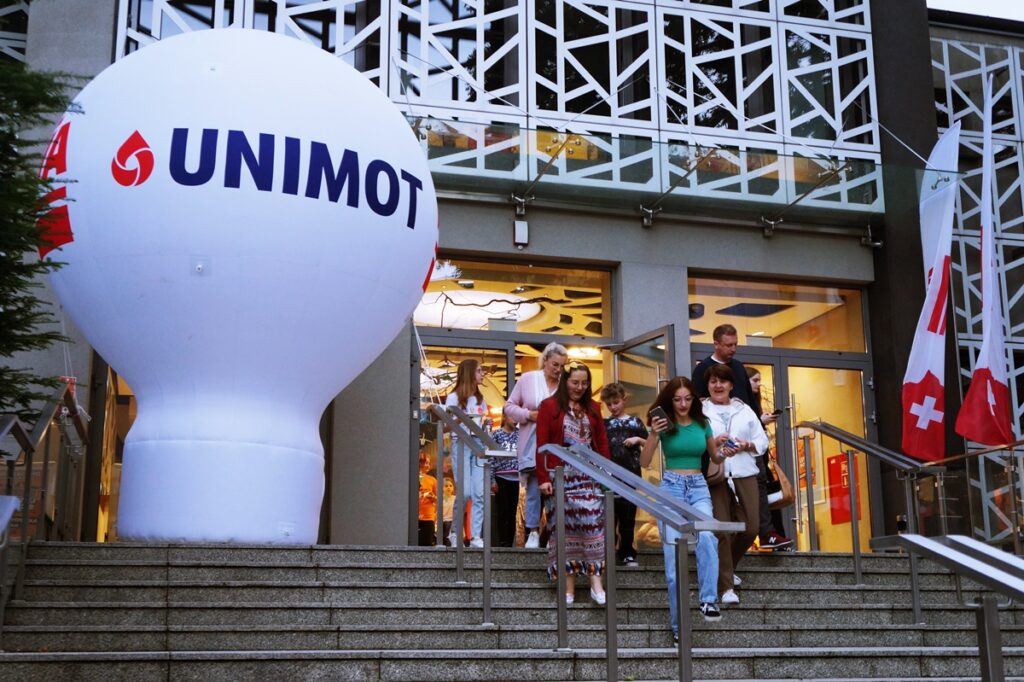 Grupa osób wychodząca z budynku Jasielskiego Domu Kultury.  Obok  stoi duży biały, dmuchany balon firmy Unimot. 
