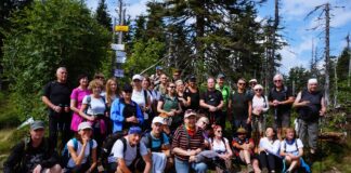 Zwiedzanie z KK-T JDK i PTTK: u stóp „Królowej Beskidów” Radośni turyści pozują do zdjęcia na szczycie – Polica.