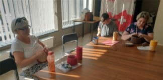 Pierwszy sezon Pracowni Edukacji Twórczej zakończony Obraz zawiera: Trzy osoby, dwie panie i jeden pan szydełkują przy stole. Naprzeciwko każdej z osób stoją szpulki nici potrzebne do wykonywania prac.