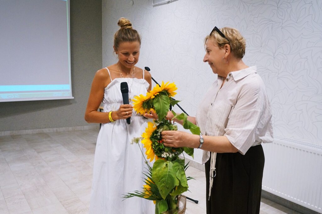 Pani Elżbieta Ruszała, pracownik Jasielskiego Domu Kultury, w podziękowaniu za przybycie, wręcza piękne słoneczniki Pani Ilonie. 