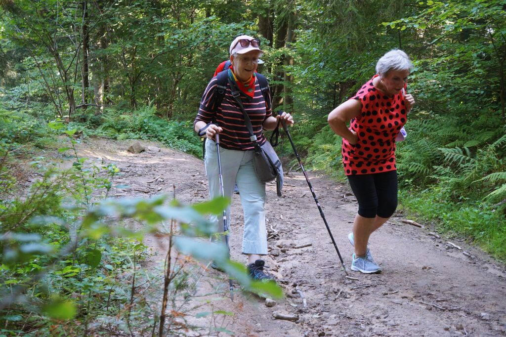 Dwie starsze kobiety wędrują górskim szlakiem. 