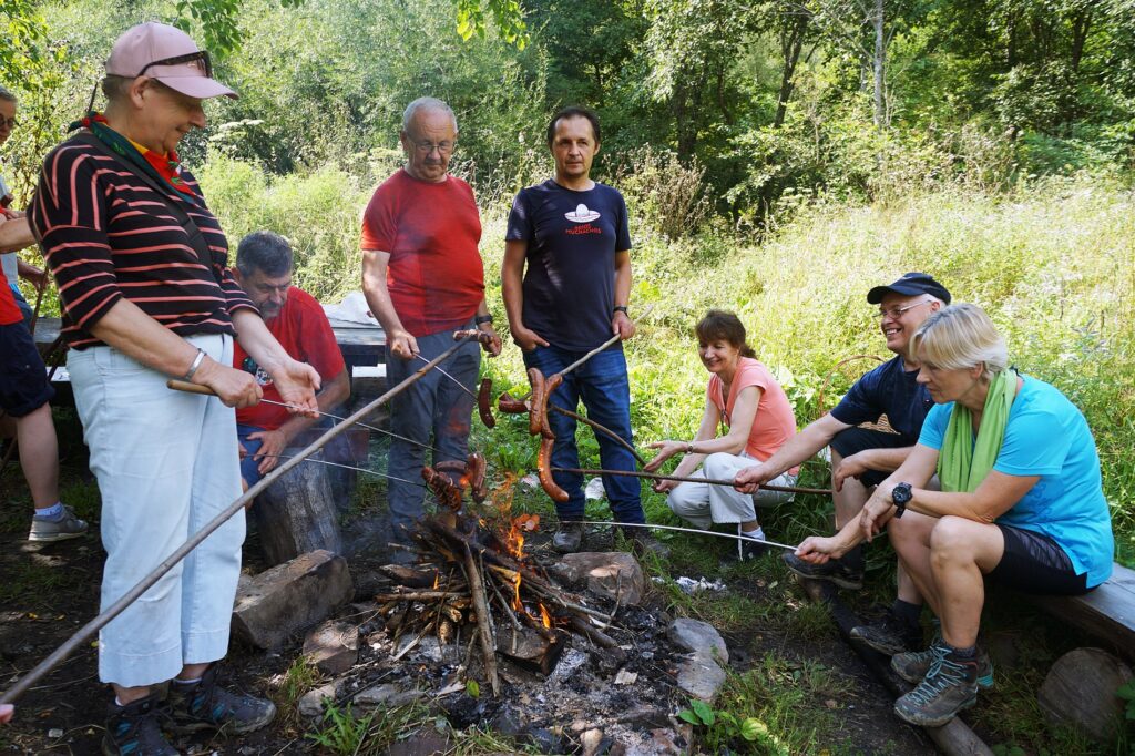 Grupa turystów piecze kiełbaski.