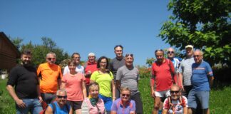 Grupa rowerzystów wraz z księdzem Tomaszem Gałuszką, pozują do wspólnego zdjęcia.