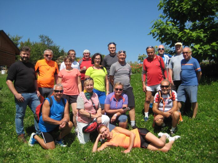grupa na tle gospodarstwa pasiecznego z ks. Tomaszem Gałuszka Grupa rowerzystów wraz z księdzem Tomaszem Gałuszką, pozują do wspólnego zdjęcia.