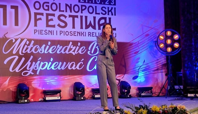 Karolina 1 Obraz zawiera: Młoda dziewczyna w spodniach i marynarce stoi na scenie i śpiewa do mikrofonu trzymanego w prawej ręce podczas 11 Ogólnopolskiego Festiwalu Pieśni i Piosenki Religijnej.