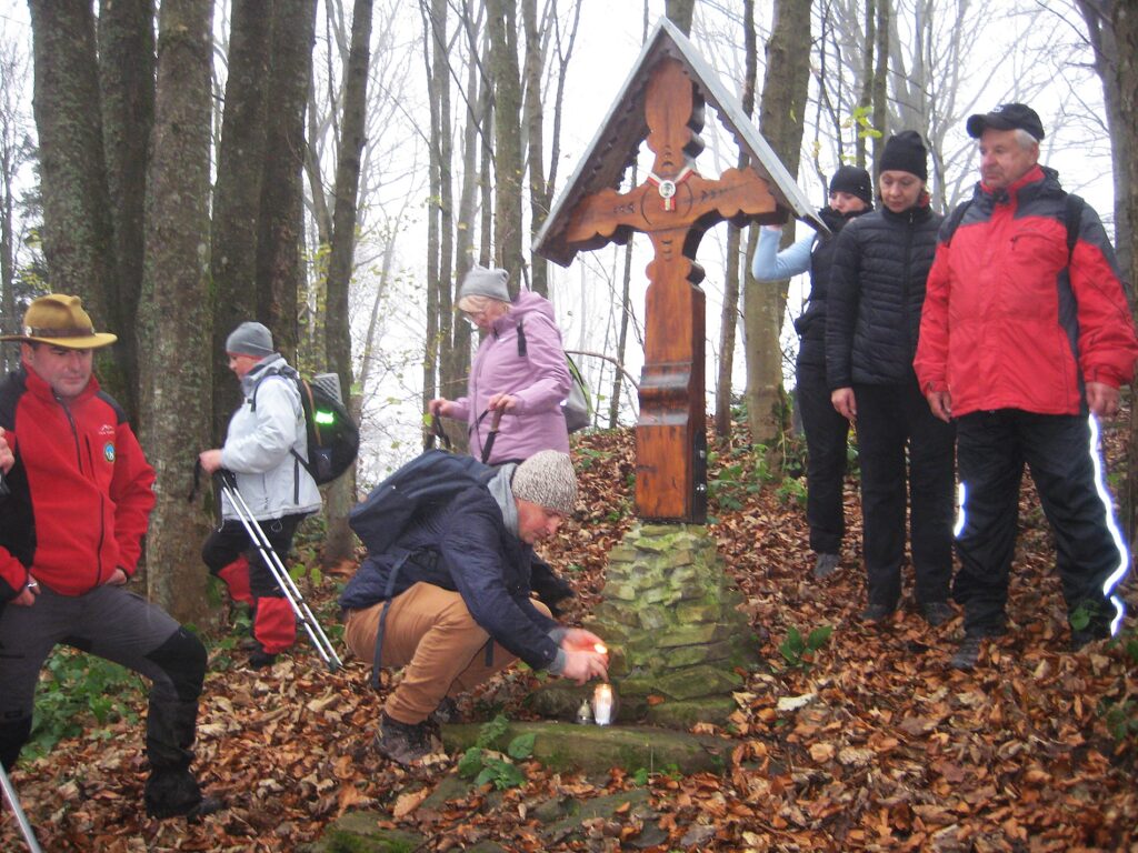 Turyści przy krzyżu upamiętniającym ofiary wielkiej wojny.