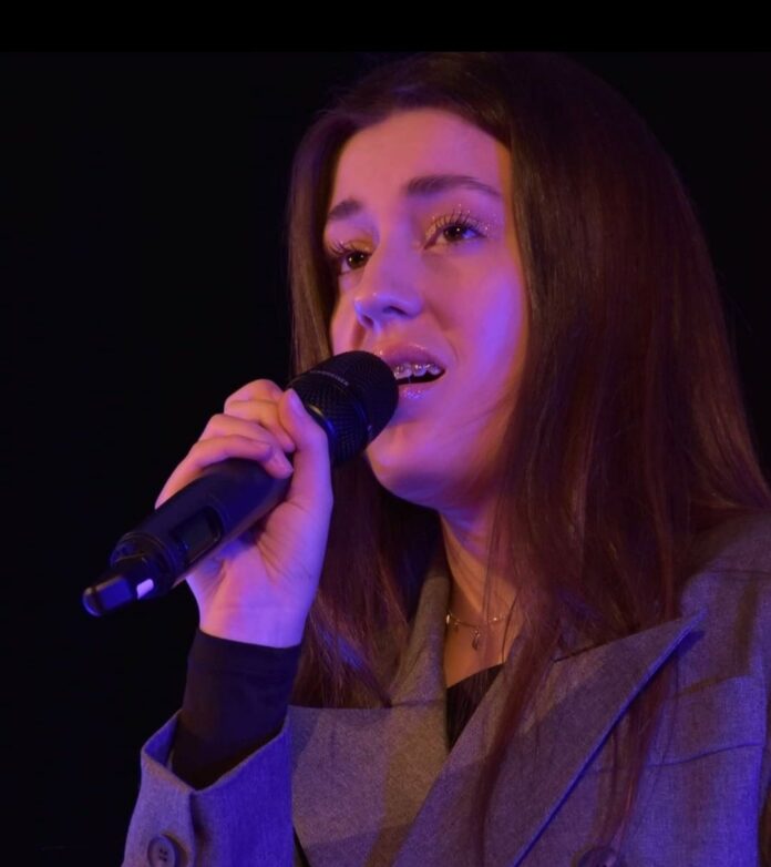 Sedziszów_2 ikonka Obraz zawiera: Karolina Polak śpiewa do mikrofonu, trzymanego w prawej ręce.