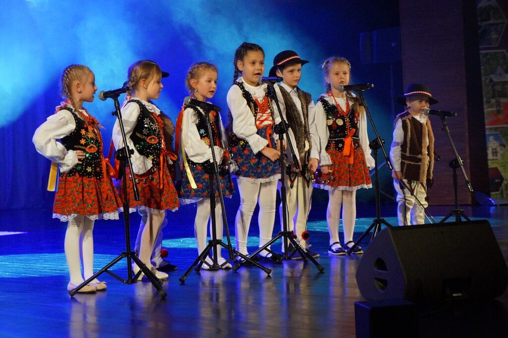 Grupa przedszkolaków w strojach góralskich na scenie. dzieciaki śpiewają wspólnie kolędę.