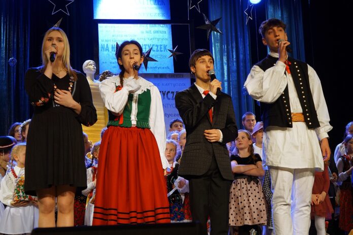 DSC00736 Czterech laureatów na scenie: dwie młode dziewczyny i dwóch chłopaków. Wszyscy śpiewają wspólnie kolędę.
