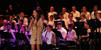 Na scenie jasielskiego domu kultury gra młodzieżowa orkiestra. Muzycy ubrani są w białe koszule i czarne spodnie. Przed nimi stoi solistka Karolina Polak w złotej sukience i śpiewa kolędę do mikrofonu