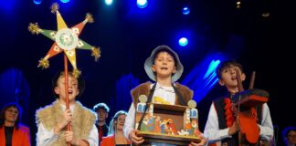 Trzech chłopców śpiewa kolędę. Dzieci przebrane są za kolędników.