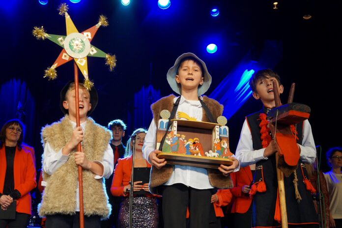 DSC01178 Trzech chłopców śpiewa kolędę. Dzieci przebrane są za kolędników.