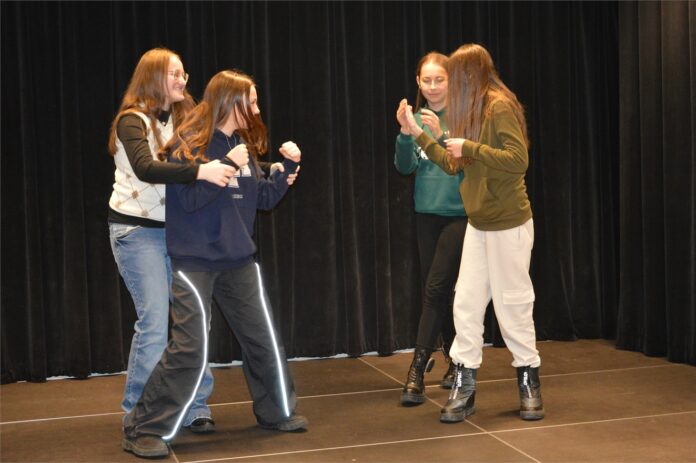 Warsztaty teatralne Level Up_3 Obraz zawiera: Cztery młode dziewczyny na scenie teatralnej prezentują przygotowaną podczas warsztatów scenkę rodzajową.