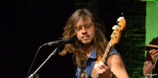 Obraz zawiera: Gitarzysta i wokalista Yellow Horse przed mikrofonem podczas koncertu w sali offowej JDK.