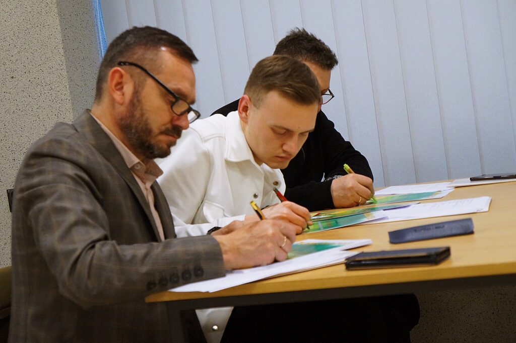 Członkowie jury podpisują pamiątkowe dyplomy.