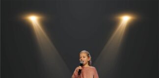 Lena i Karolina nagrodzone w Przemyślu Dziewczynka stoi na scenie w świetle reflektorów i śpiewa do mikrofonu