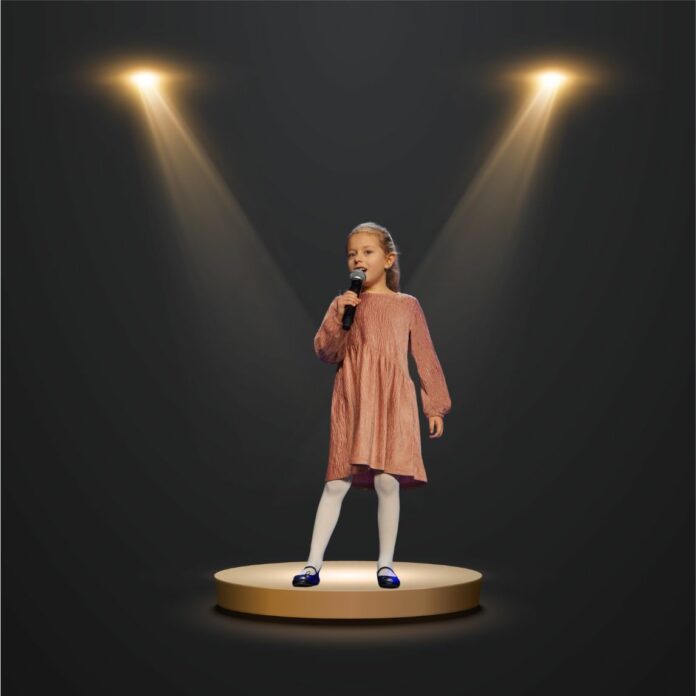 Dziewczynka stoi na scenie w świetle reflektorów i śpiewa do mikrofonu